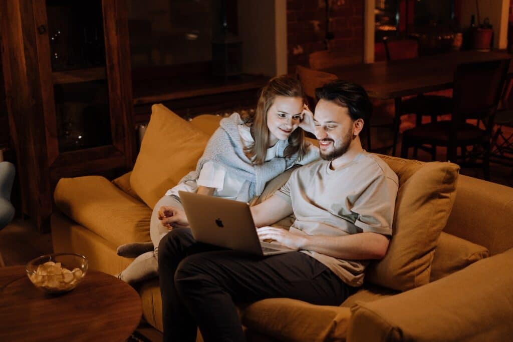 Couple Sitting on a Couch in Front of a laptop
